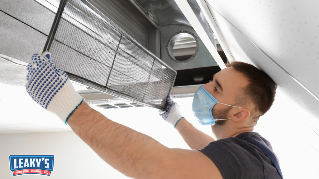 A Man Taking Down an Air Duct Filter
