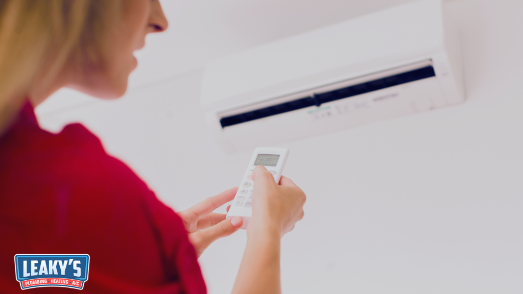 Person adjusting a split air conditioner with a remote.